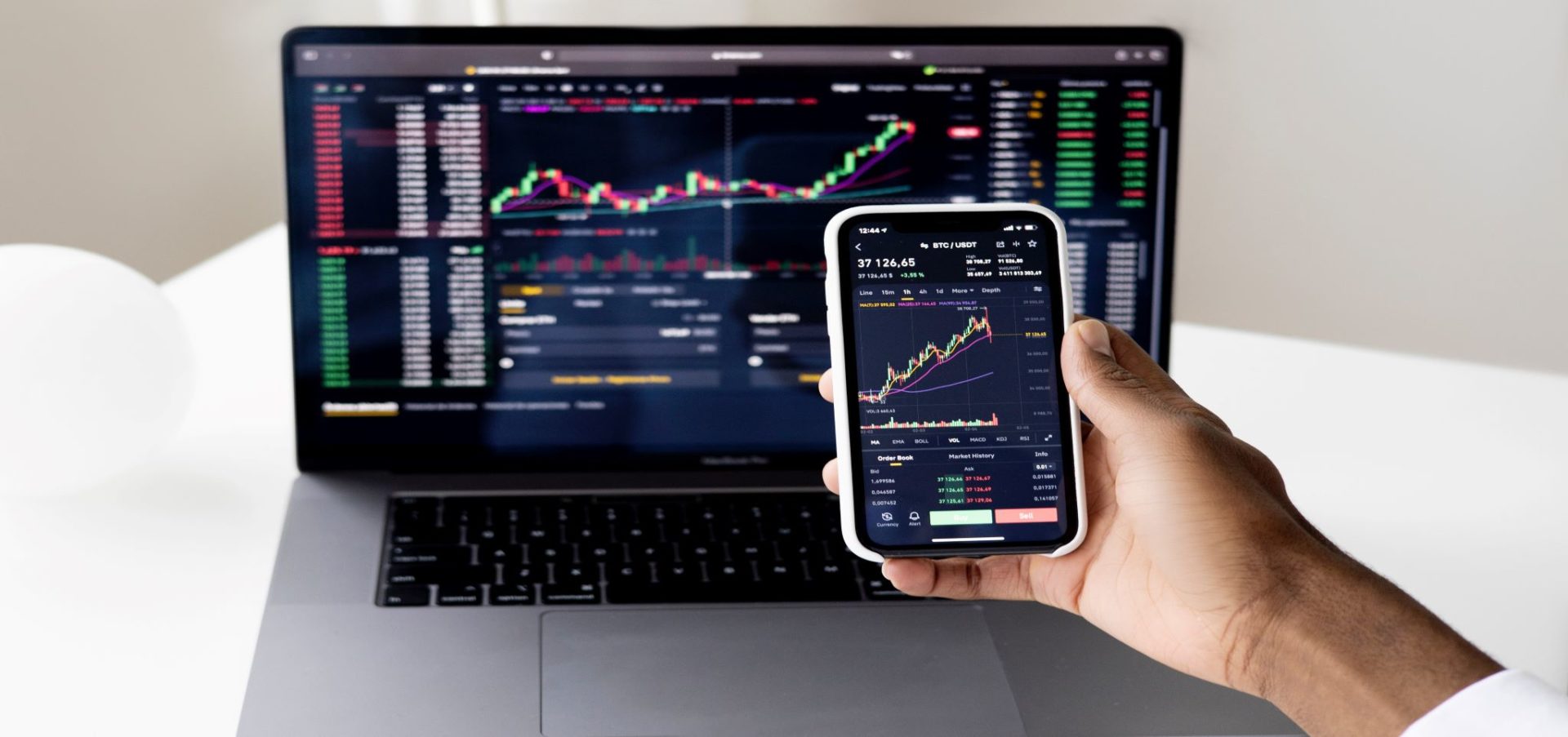 Phone and computer with line graphs tracking fixed-income investments
