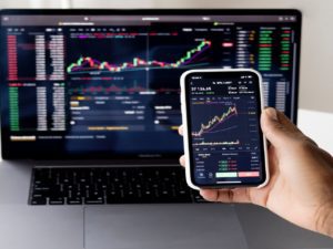 Phone and computer with line graphs tracking fixed-income investments